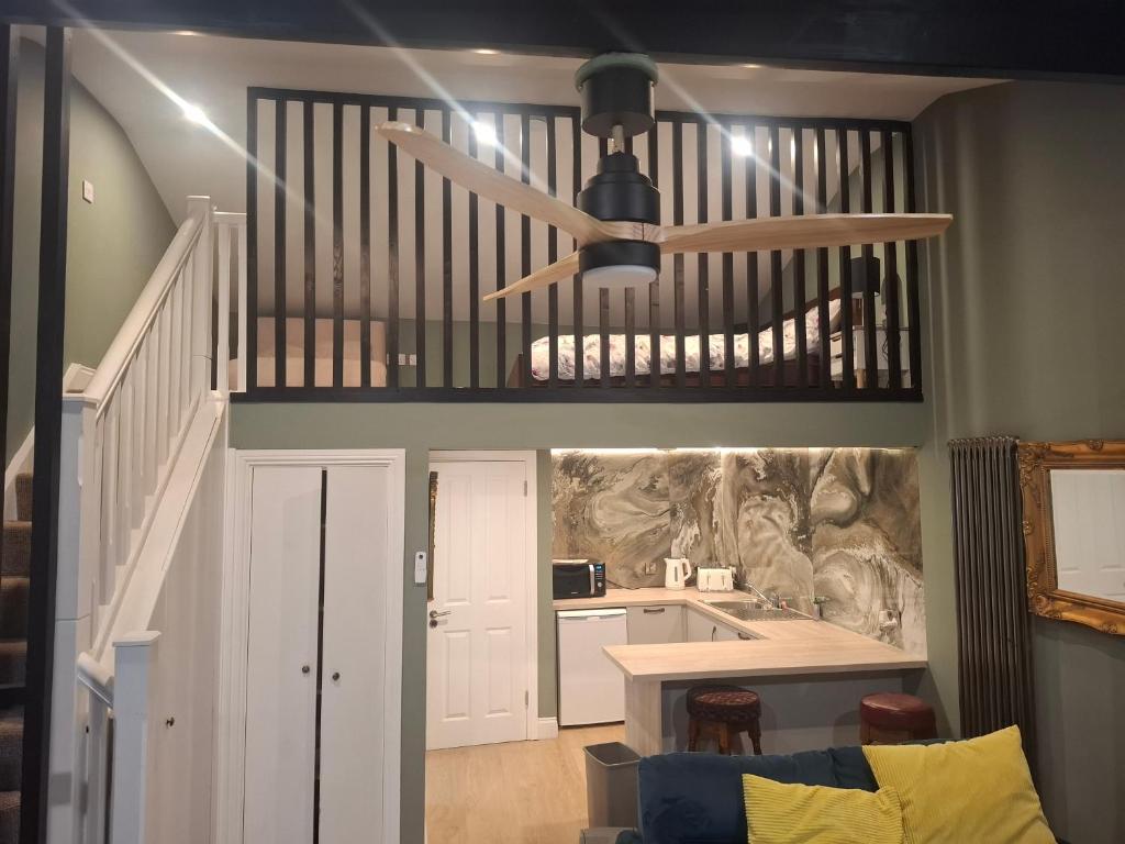 a living room with a ceiling fan and a kitchen at Tramway Apartment in Blessington