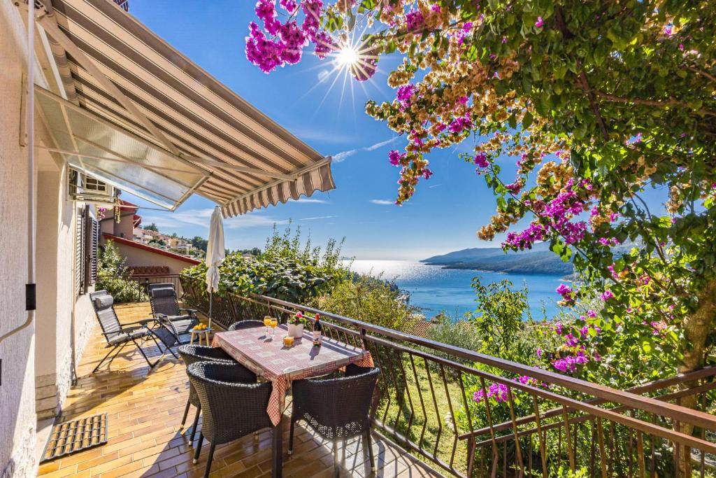 a balcony with a table and chairs and a view of the ocean at Apartment Neda in Rabac - Bay View in Rabac
