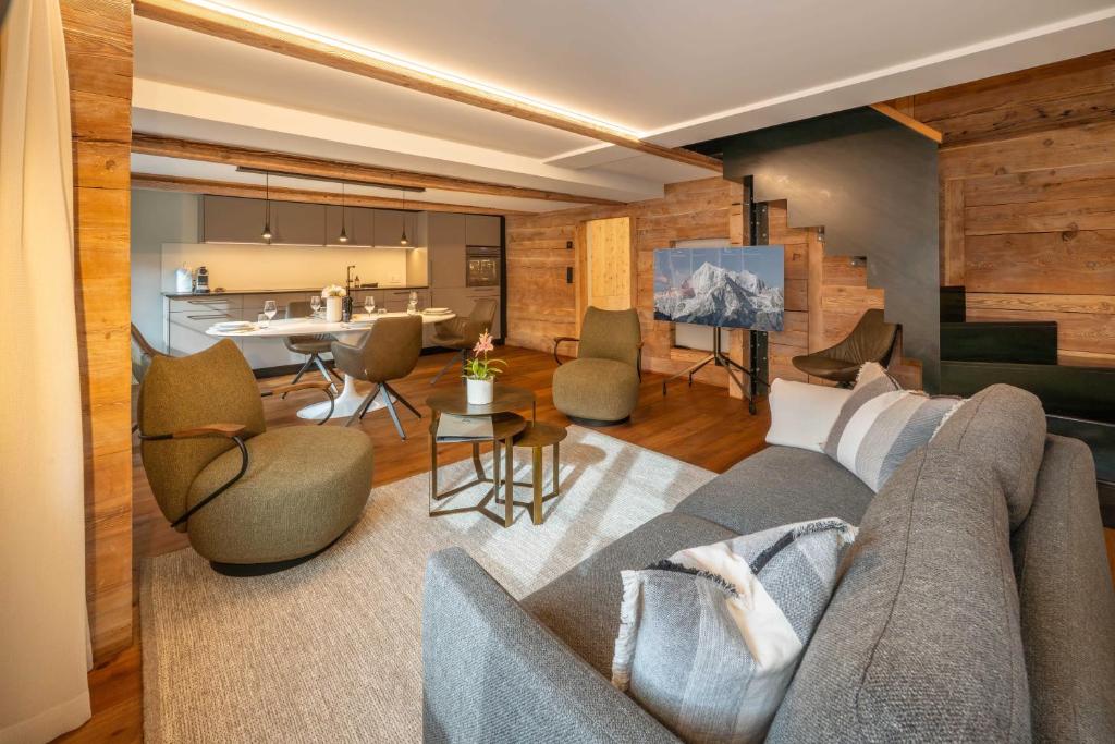 a living room with a couch and chairs and a kitchen at The Maisonette, the luxury edition in the center by Inspiring Places Zermatt in Zermatt