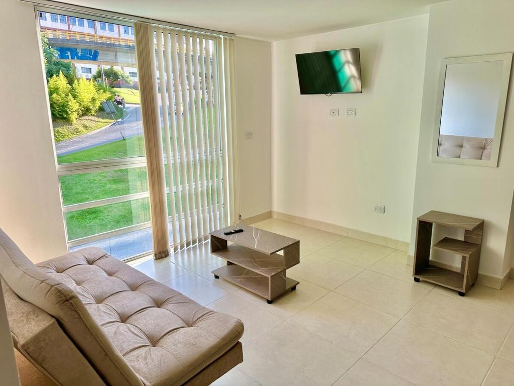a living room with a couch and a large window at Lindo apartamento en excelente zona Central Urban Mzles in Manizales