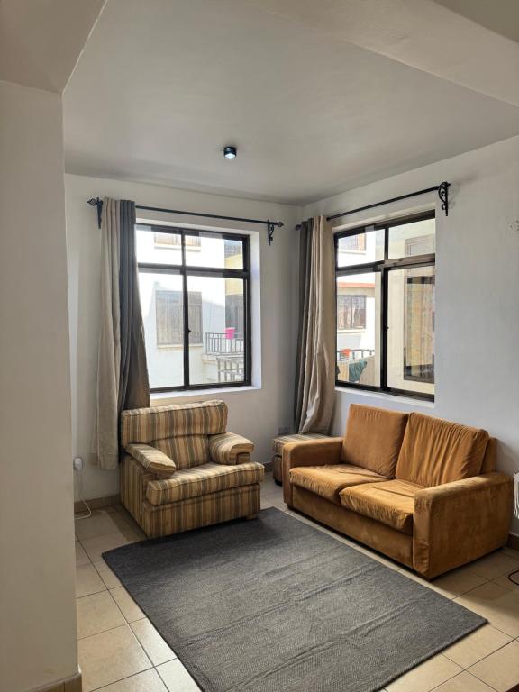 a living room with two couches and two windows at Pumzika Town House in Arusha