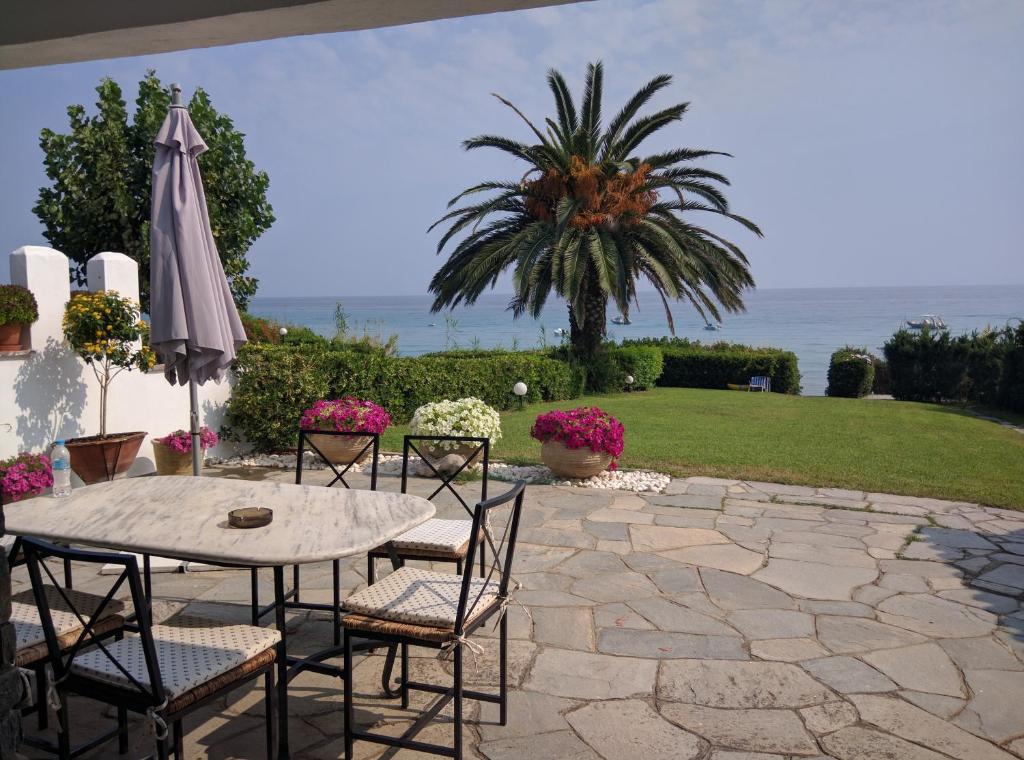 a patio with a table and chairs and an umbrella at Beach Front Chanioti in Polykhrono