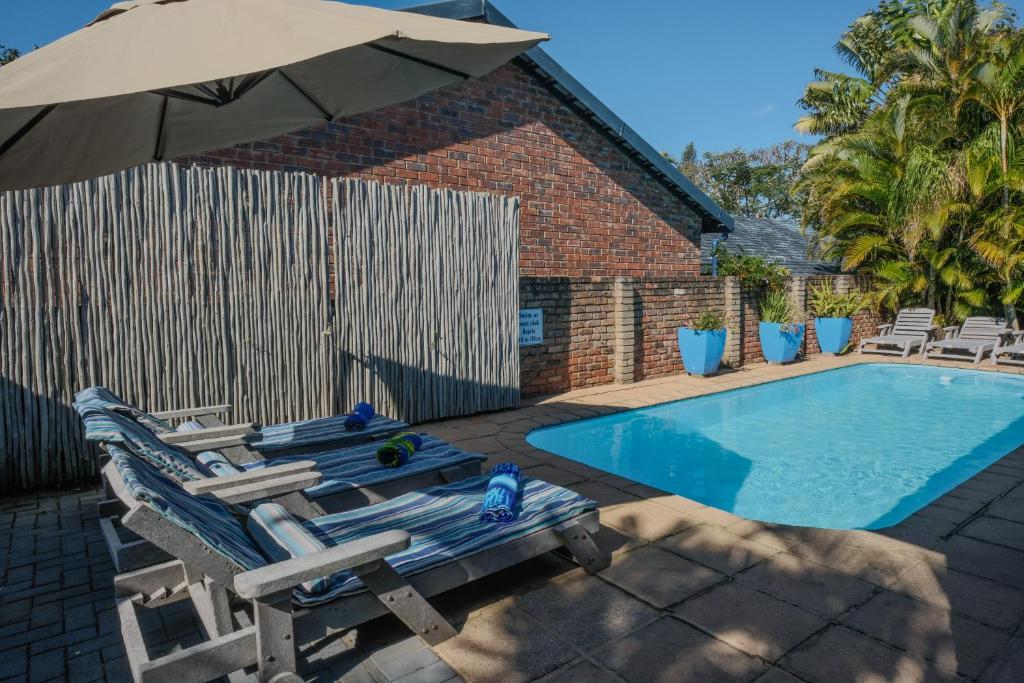 a swimming pool with two lounge chairs and an umbrella at Marlin Lodge St Lucia in St Lucia