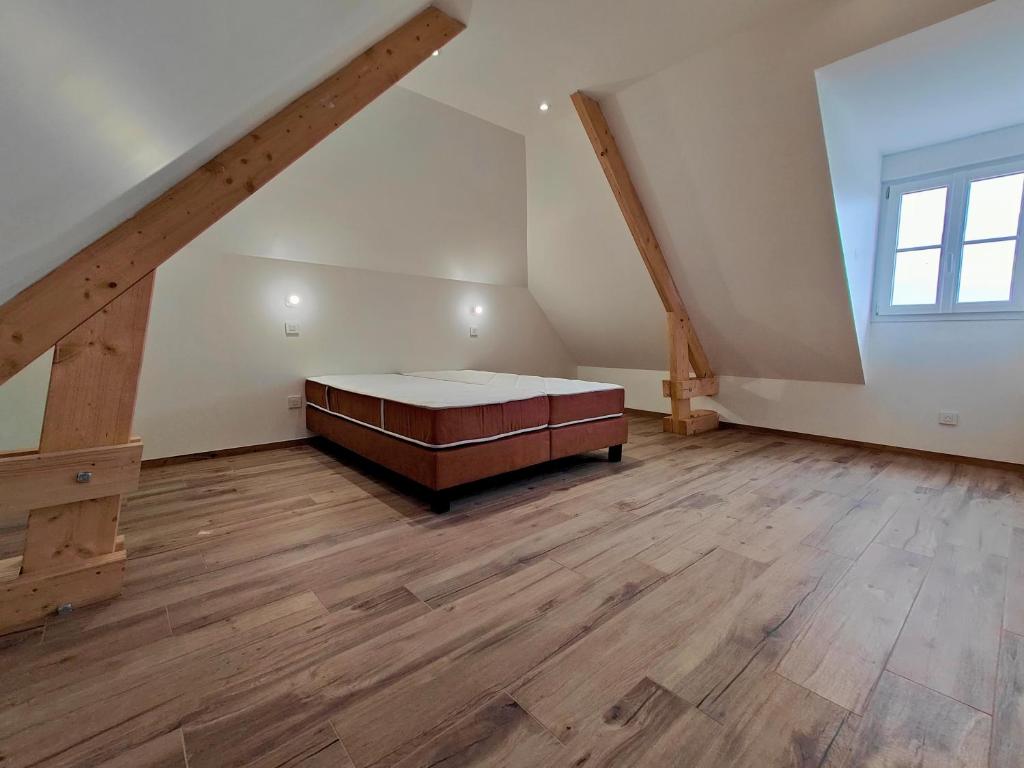 een grote zolderkamer met een bed en een raam bij Gite des Polders in Saint-Quentin-en-Tourmont