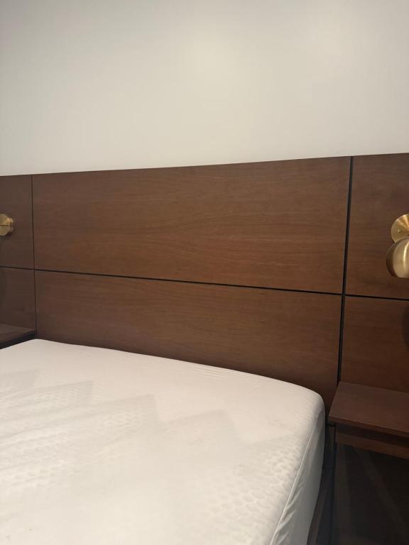 a bed with a wooden headboard and white sheets at Hotel AlFari in Tijuana