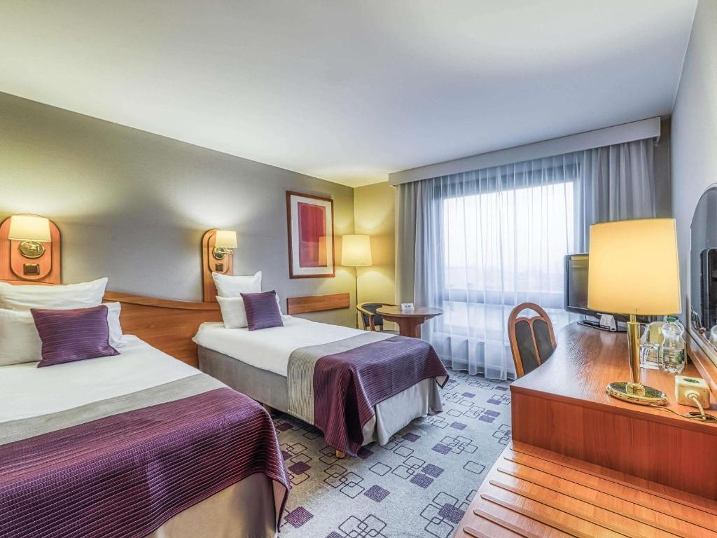 een hotelkamer met twee bedden en een televisie bij Mercure Cieszyn in Cieszyn