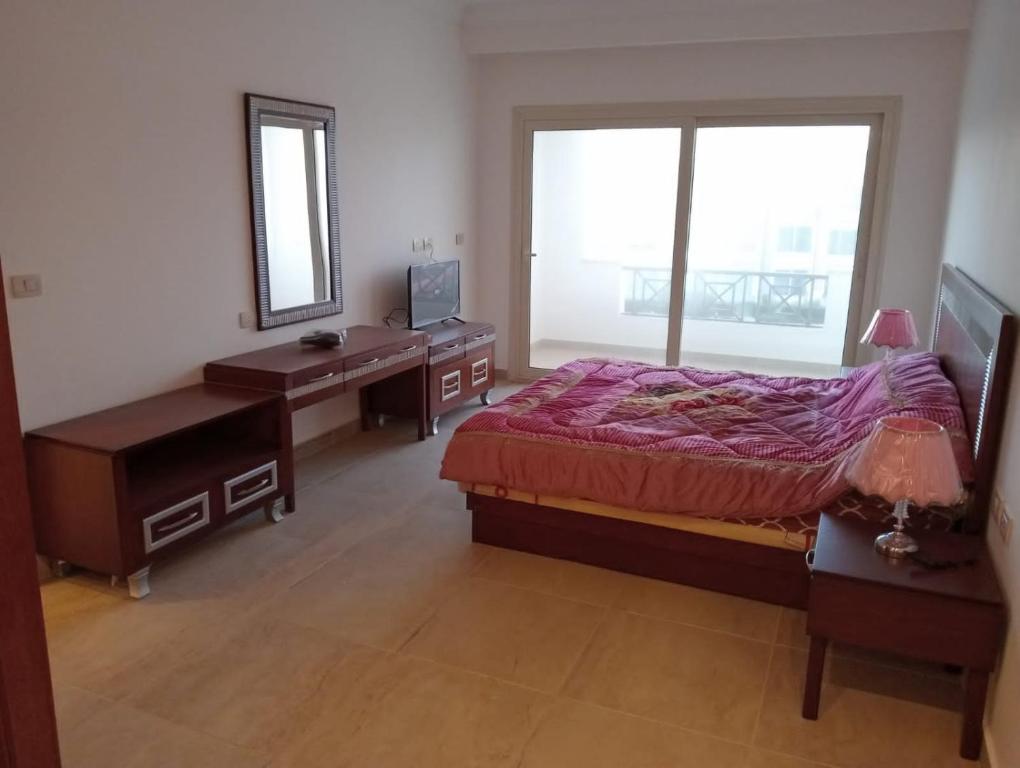 een slaapkamer met een bed, een bureau en een spiegel bij شاليه مرسى علم in Marsa Alam