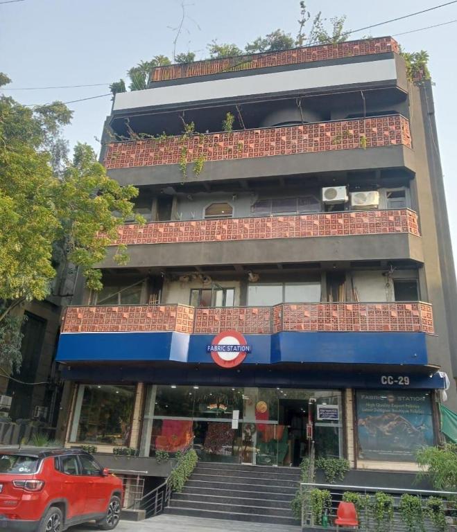 a building with a red car parked in front of it at Bluestone Prime by The Cosy Hotels in New Delhi