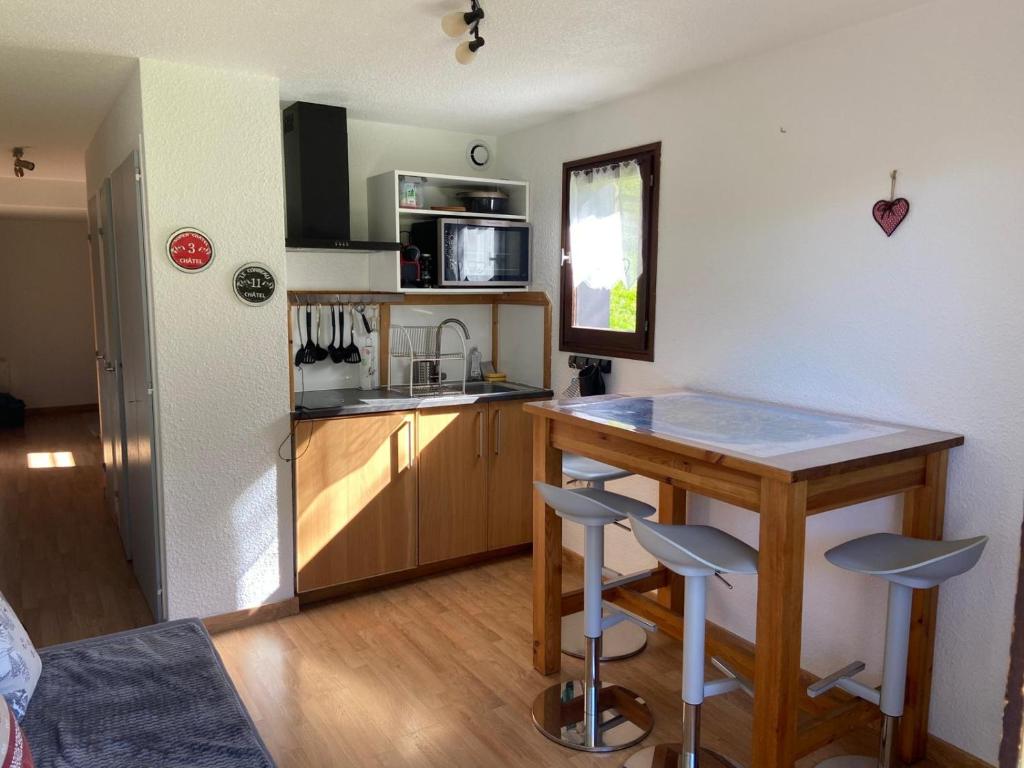 a small kitchen with a counter and a table with stools at Toison Blanche TBC45 COSY & Mountain 4 Pers in Châtel