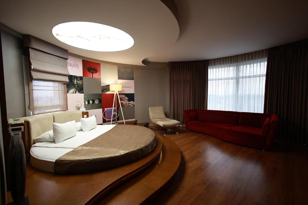 a bedroom with a large bed and a red couch at Orucoglu Oreko Hotel in Manisa