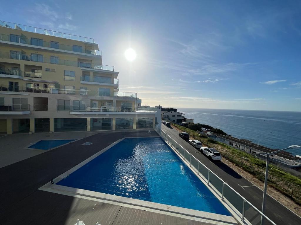 a building with a swimming pool next to the ocean at A-MO Sesimbra by Trip2Portugal in Sesimbra