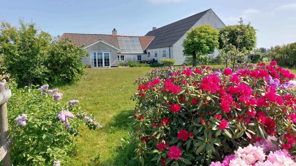 a house with a bunch of flowers in a yard at Holiday In A Cozy Farmhouse With Horses in Bøvlingbjerg