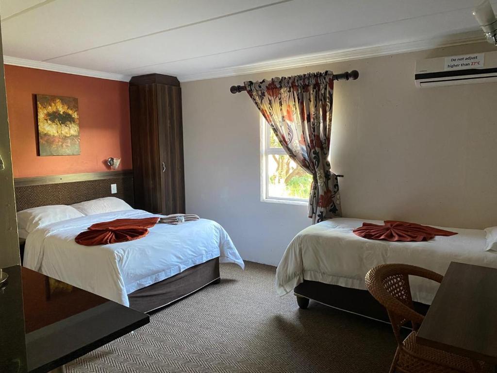 Una habitación de hotel con dos camas y una ventana. en Be My Guest Hotel Conference, en Sasolburg