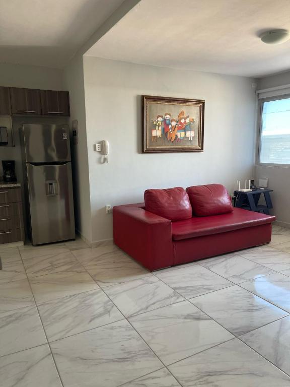 a living room with a red couch and a refrigerator at Brisa Marina Departamento con Alberca y Playa in Boca del Río