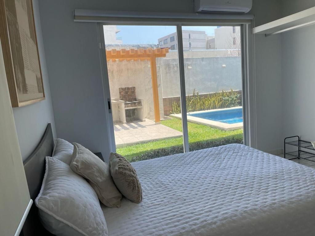 a bedroom with a bed and a large glass window at Brisa Marina Departamento con Alberca y Playa in Boca del Río