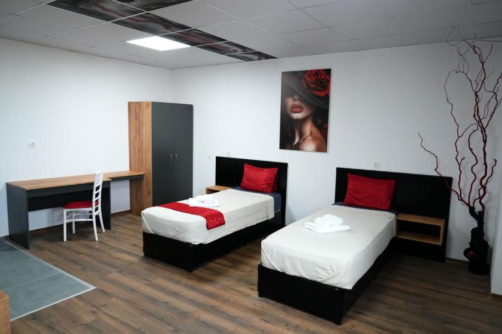 a room with two beds and a desk with a chair at Хостел Цанови in Pleven