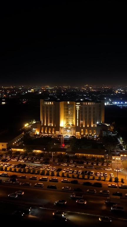 een parkeerplaats met een groot gebouw 's nachts bij فندق قصر الخورنق in An Najaf