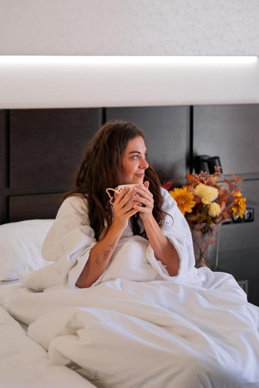 弗林布尔克福林布鲁克酒店的躺在床上喝一杯咖啡的女人