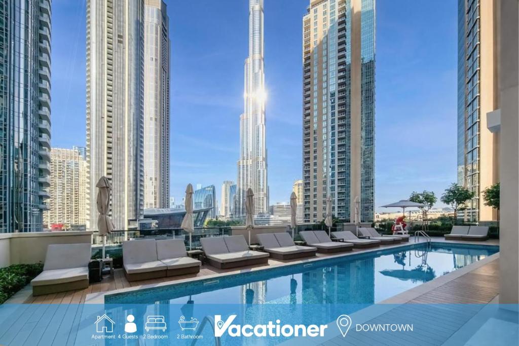 a swimming pool with lounge chairs and a city skyline at Vacationer l Vibrant 2 Bedroom l Pool with Burj Khalifa View in Dubai