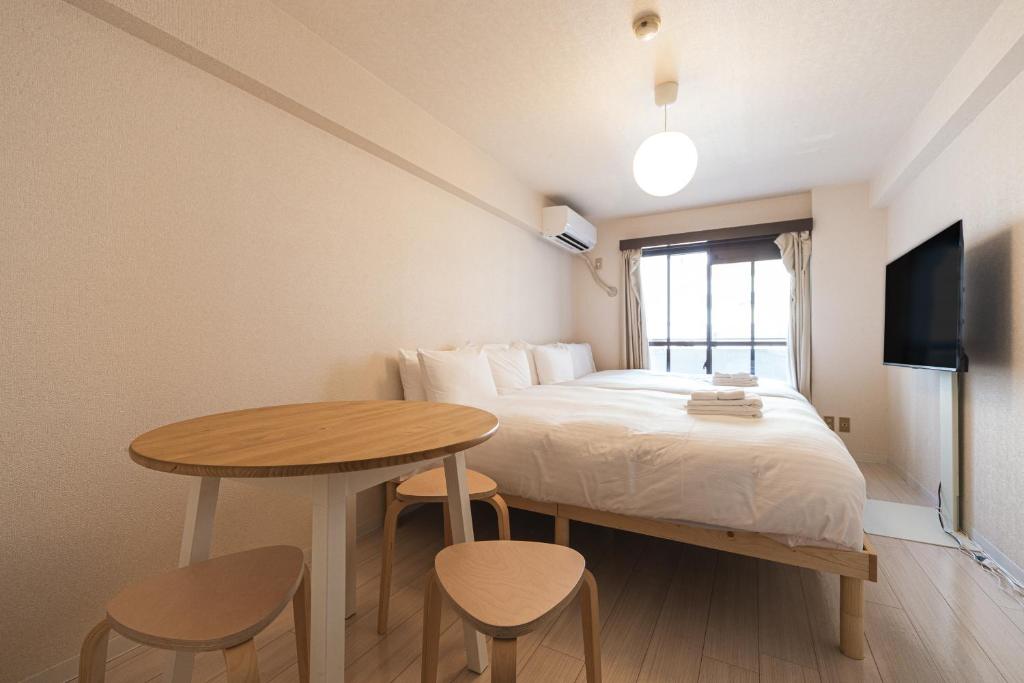 a small bedroom with a bed and a table at Eruza HAKATA エルザ博多 in Fukuoka