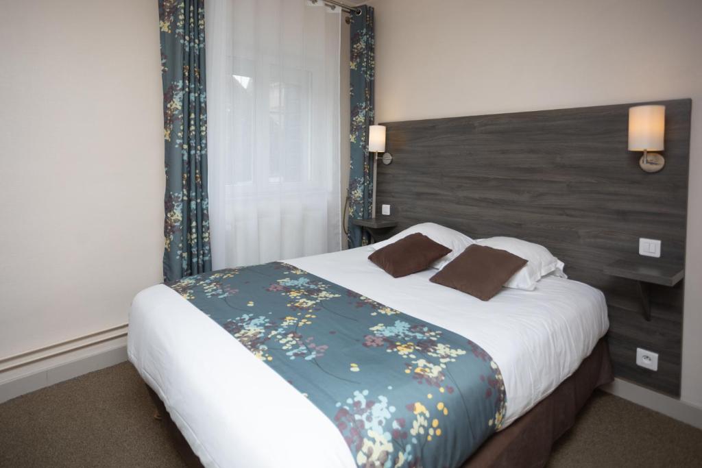 a bedroom with a large bed with a floral blanket at Logis-Hôtel & Restaurant LE CARNOT in Bolbec