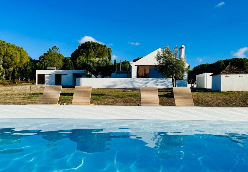 a group of chairs sitting next to a swimming pool at Fazenda do Pomar by Trip2Portugal in Montemor-o-Novo