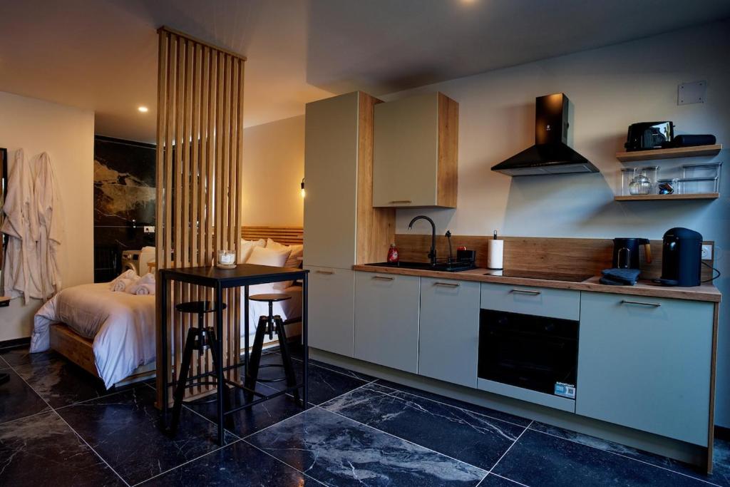 a kitchen with a table and a bed in a room at Instinct Sauvage - Nature & Jacuzzi privatif in Verdun