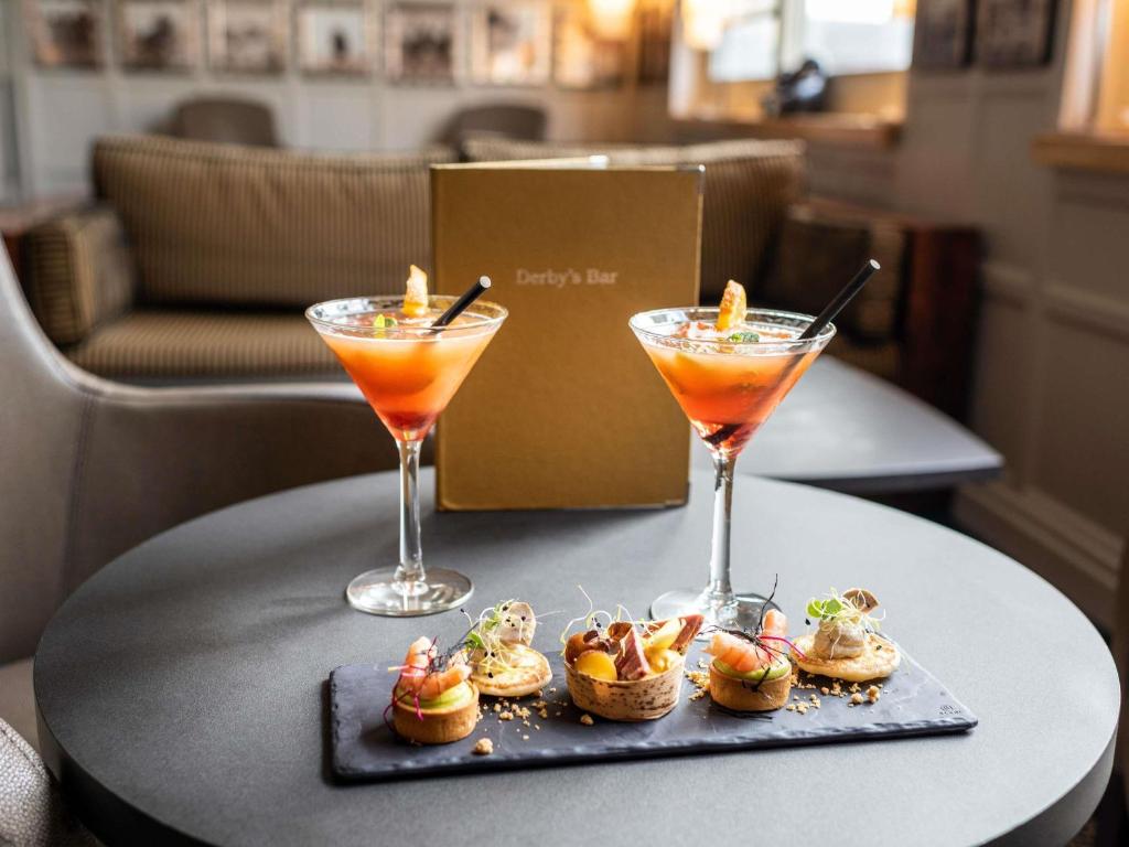 two cocktails and a tray of food on a table at Hotel Mercure La Baule Majestic in La Baule
