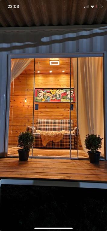 a room with a bed and two potted plants at Casa Container Branca in Bagé