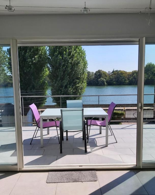 a patio with a table and chairs and a view of the water at Apartment L'Aquarius in Villeneuve-le-Roi