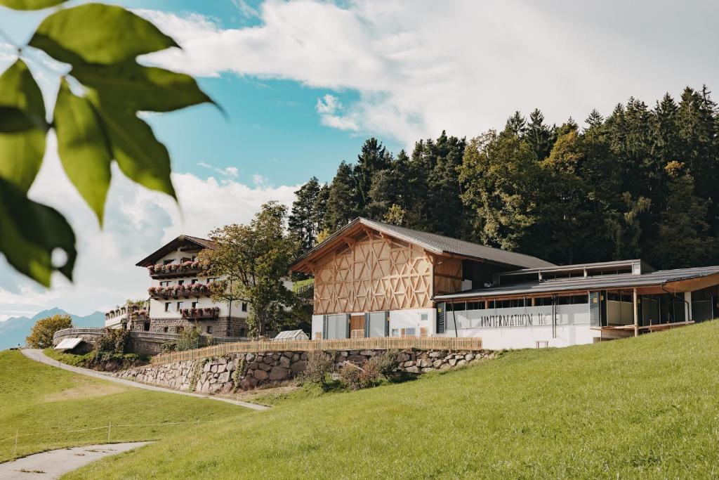 a house on top of a hill with a stone wall at Untermathonhof Vöran - Apartments with Farmyard Experience and homemade Breakfast in Verano
