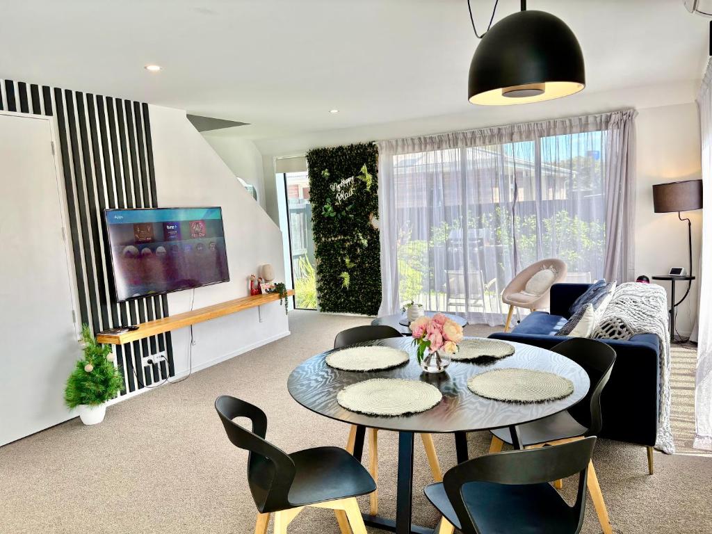 een woonkamer met een tafel en stoelen bij Travellers' dream steps from shops and close to Airport in Christchurch