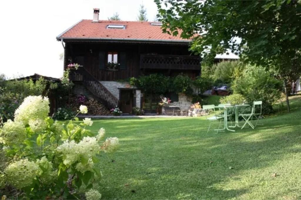 a house with a garden and a table in the yard at La Mutelline - Les Carroz in Arâches-la-Frasse