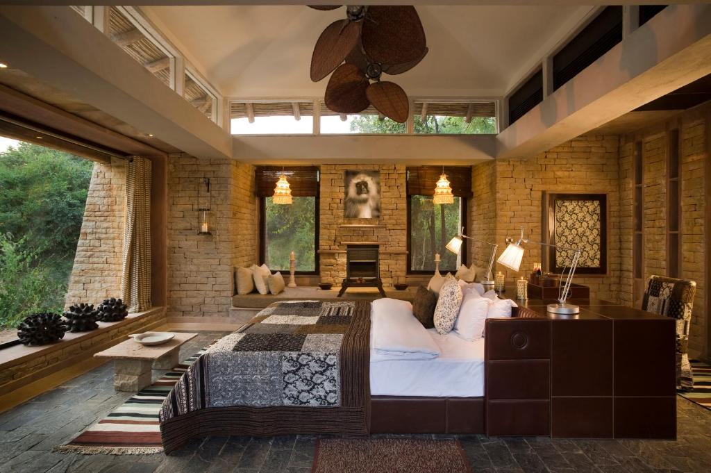 ein Schlafzimmer mit einem großen Bett und einer Ziegelwand in der Unterkunft Pashan Garh Panna National Park - A Taj Safari Lodge in Panna