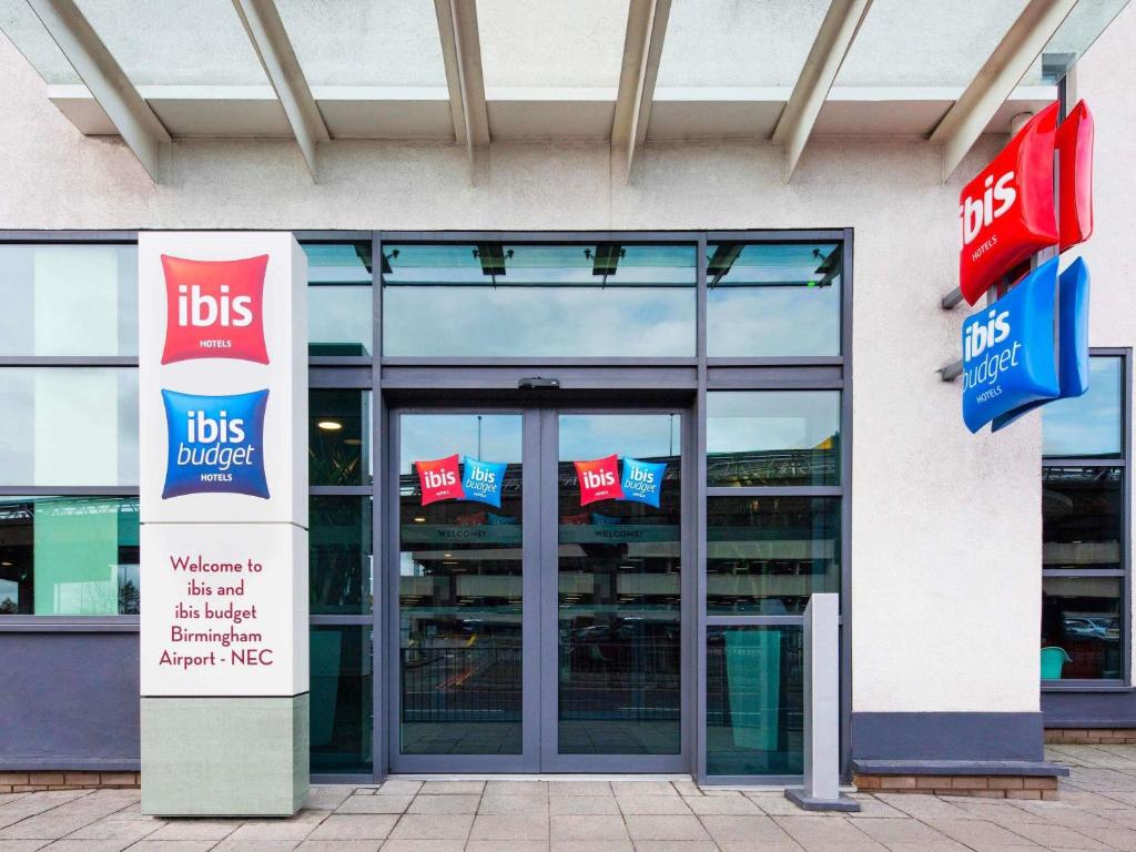 a building with glass doors and signs in front of it at ibis Birmingham Airport Terminal Building - NEC in Bickenhill