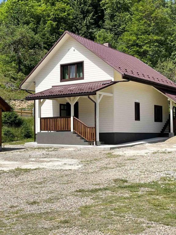 a small white house with a porch and a yard at Котедж Маєток Ярини in Krivopolʼye