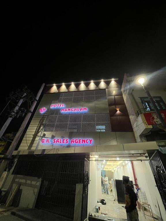 a man standing in front of a building with a sign on it at Hotel Manglam in Kota