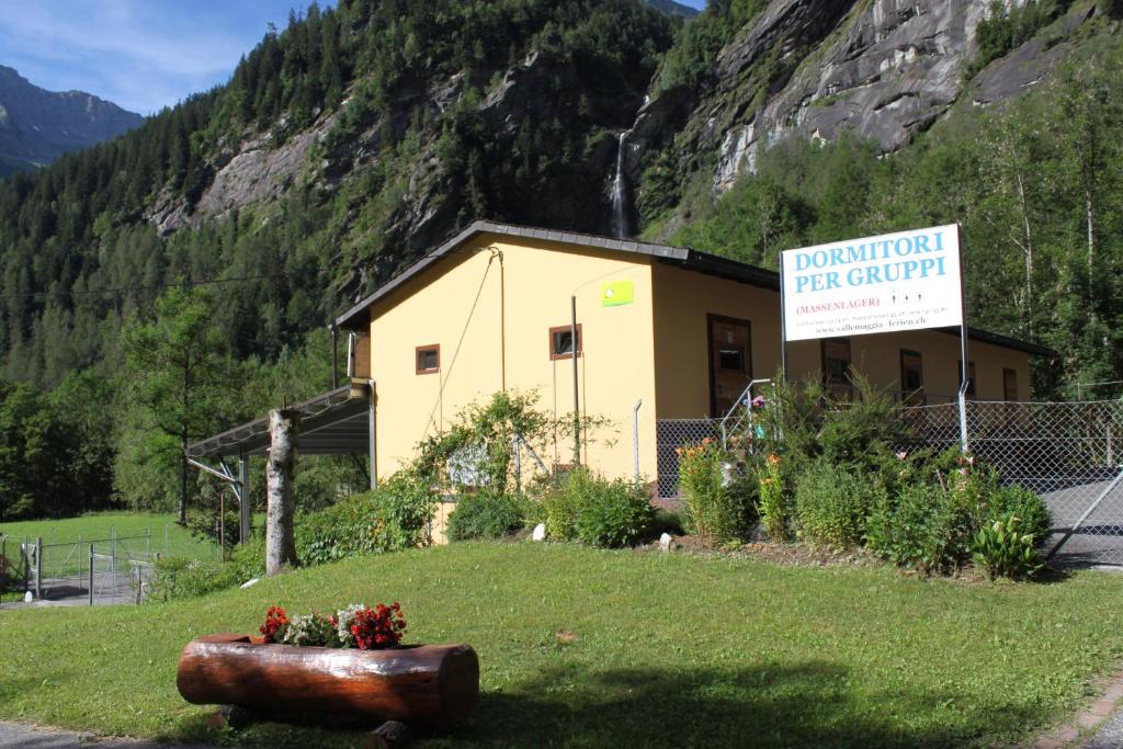 a building with a sign on the side of a mountain at Agriturismo Mattei - Dormitorio in Peccia