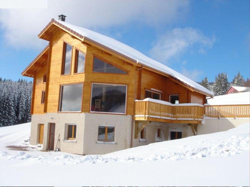 ein Holzhaus im Schnee mit Schnee in der Unterkunft Grand Valtin : chalet écolo 4 étoiles 14 personnes in Ban-sur-Meurthe-Clefcy
