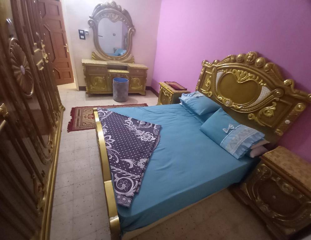 a bedroom with a blue bed with a gold headboard and a mirror at Lotus 蓮 in Abu Simbel