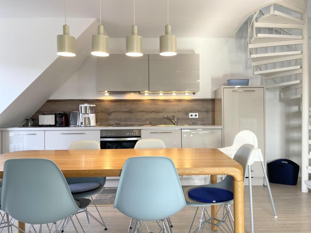 una cucina con un tavolo di legno e sedie bianche di Blankwasser 11 a Grömnitzerhagen