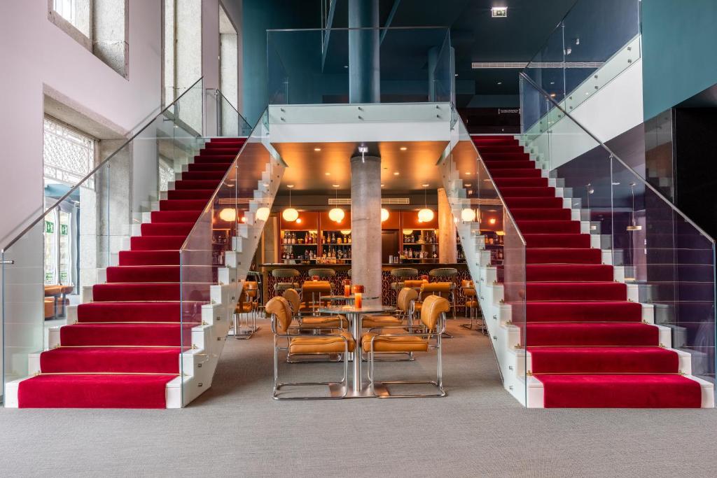 a staircase leading up to a restaurant with red stairs at Cenica Porto Hotel, Curio Collection By Hilton in Porto