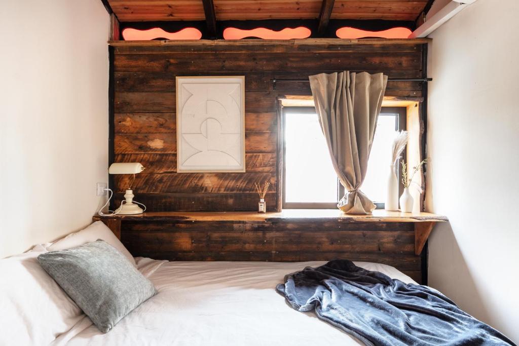 a bedroom with a bed with a wooden headboard and a window at The Urban Chalet in Tel Aviv