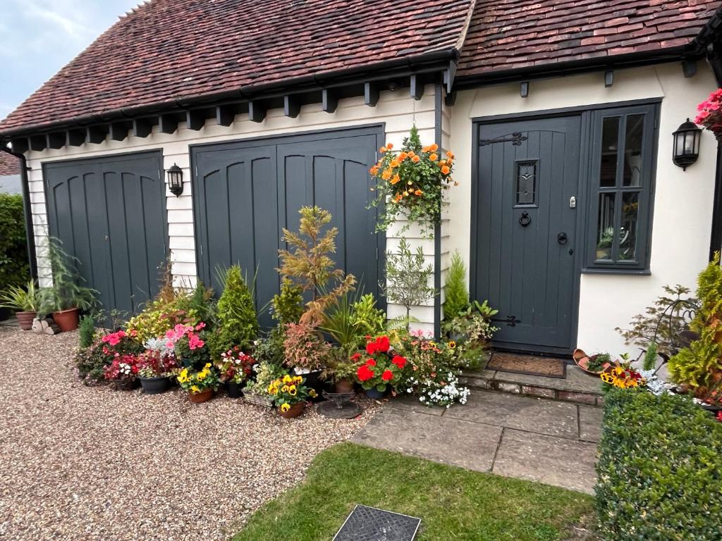 a house with two garage doors and flowers at Sunnyside Cottage in Great Sampford