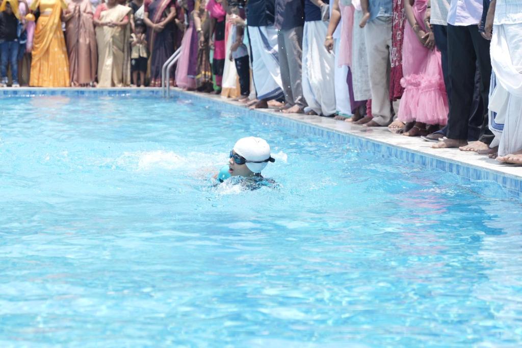 a person swimming in a swimming pool in front of a crowd at Oceanus Retreat in Kottiyam
