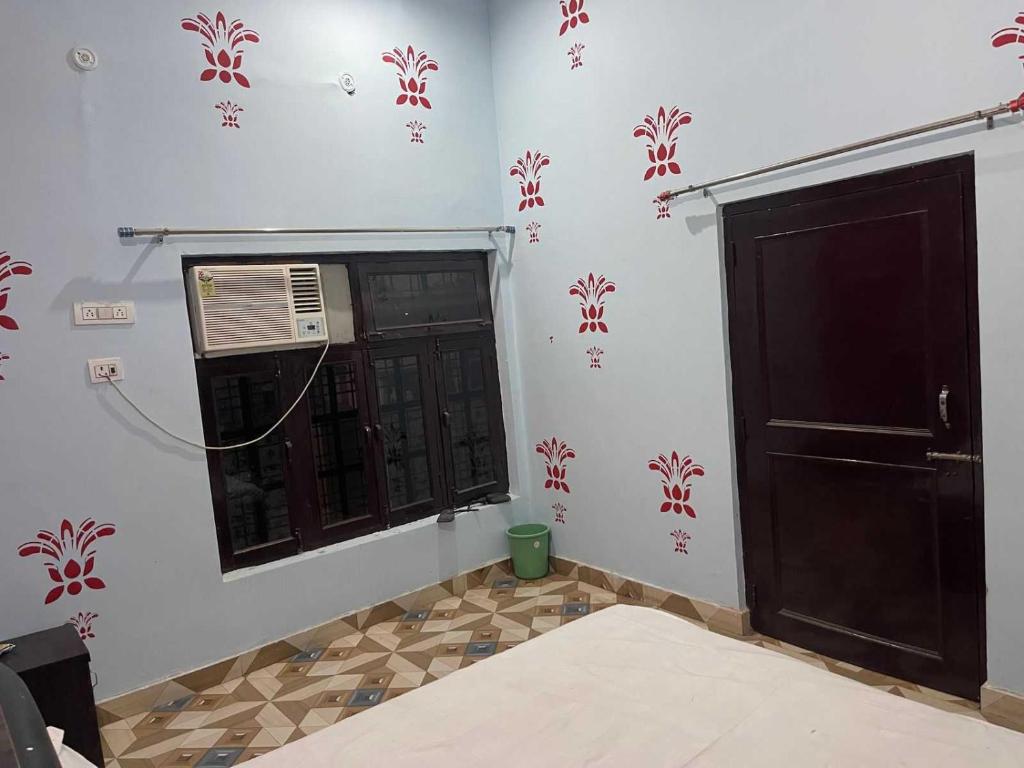 a room with a window and a door with red flowers on the wall at Hotel O The Brothers Inn in Bāra Banki