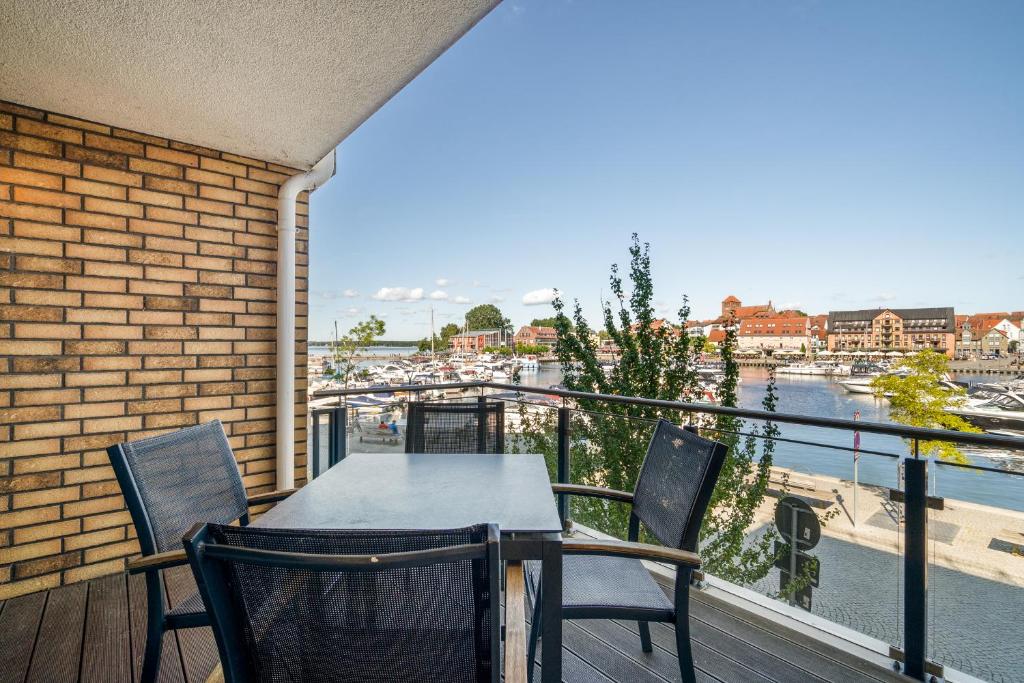 a balcony with a table and chairs and a view of a harbor at Hafenblick - Wohnung in der Hafenresidenz mit Balkon & Wasserblick in Waren