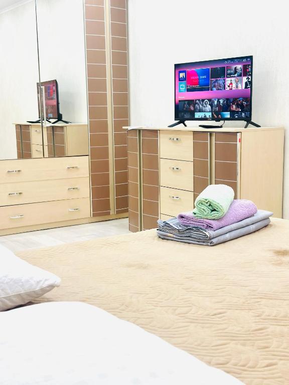 a bedroom with a bed and a tv on a dresser at City in Uralsk