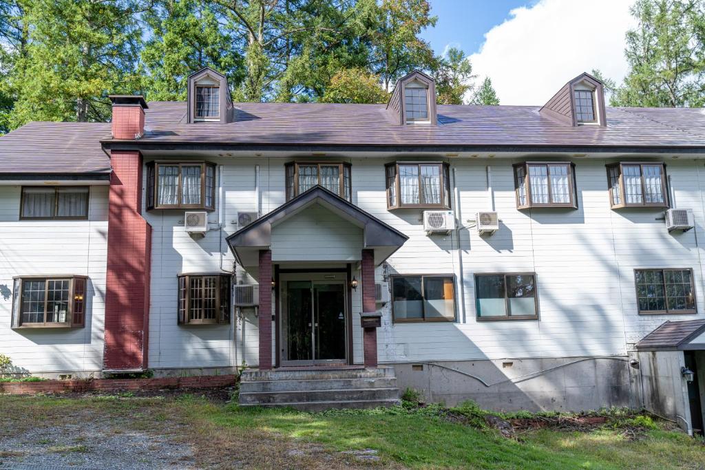 an old white house with windows and a door at ホテル白馬五竜ベース in Hakuba