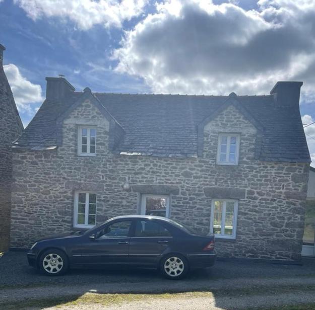 a black car parked in front of a stone house at Charmante maison de campagne in Commana